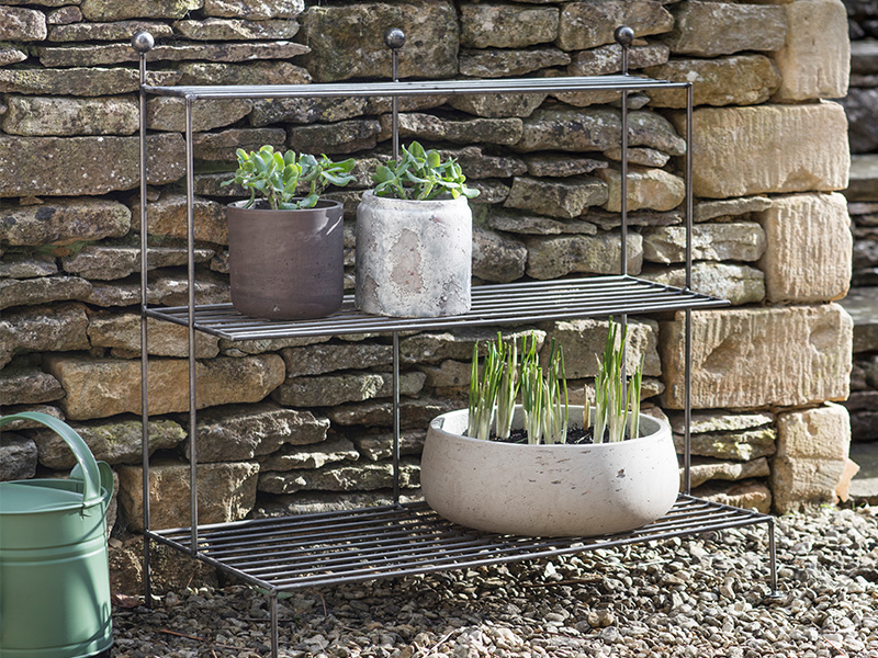 Barrington Plant Stand holding mulitple plant pots set against a cotswold stone wall