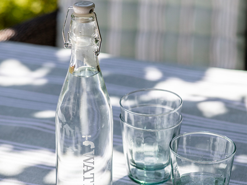 Water Tap Bottle on an outdoor table with a set of reycled glass tumblers